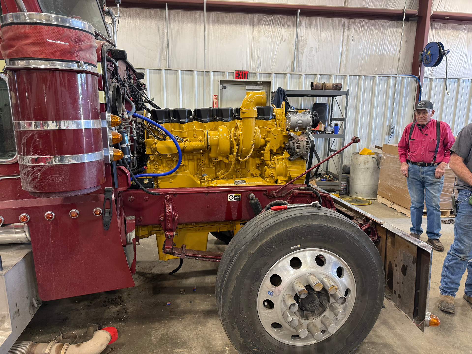 Freshly painted yellow CAT C15 diesel engine installed in a red Peterbilt at the Dreiling Field Service shop in Hays, Kansas