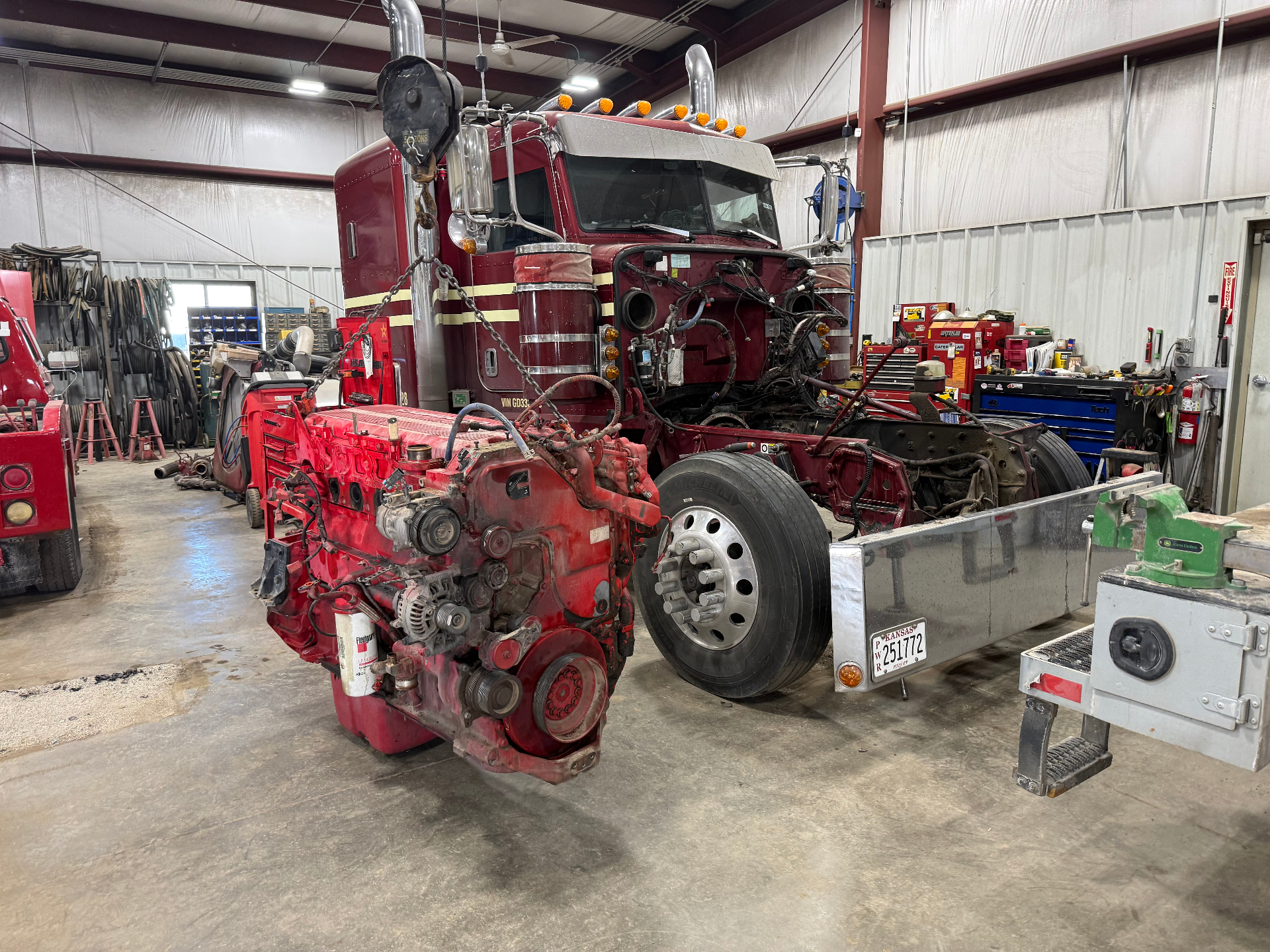 Red Peterbilt semi inside the Dreiling shop with the Cummins ISX diesel engine pulled out and sitting on the floor in front of the truck